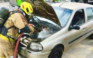 Un bombero frente a un carro que tiene el capó abierto, ya que presentó un corto circuito y estaba siendo revisado para controlar la situación.