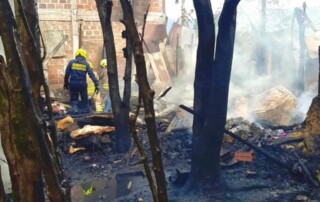 Un bombero dentro de un lote, que ha quedado completamente consumido por las llamas, debido al incendio ocurrido en un predio que funcionaba como una fabrica de colchones, arboles, paredes y suelo estan completamentes quemados